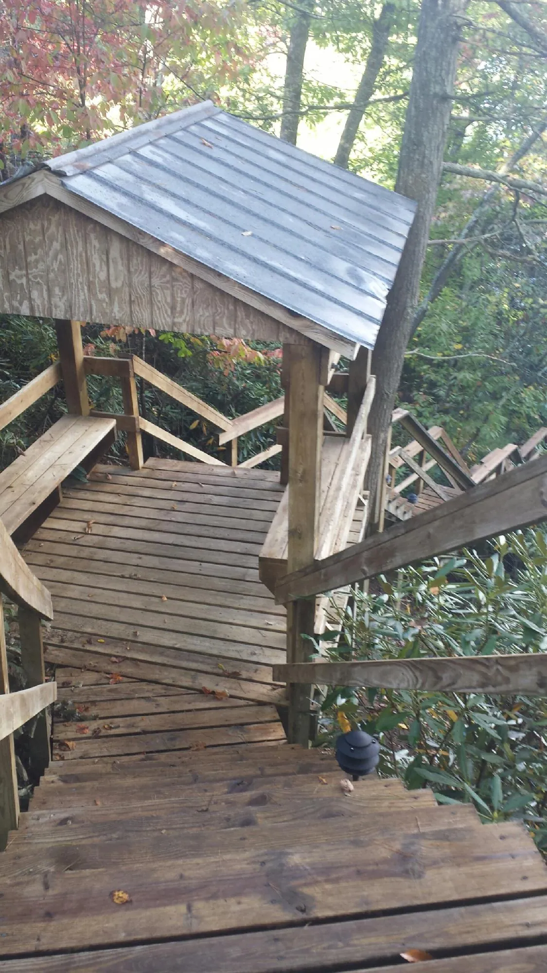 Metal roofed shelter over wooden steps on a wooded walkway — Skylight Repair & Installation work by our crew in Girard
